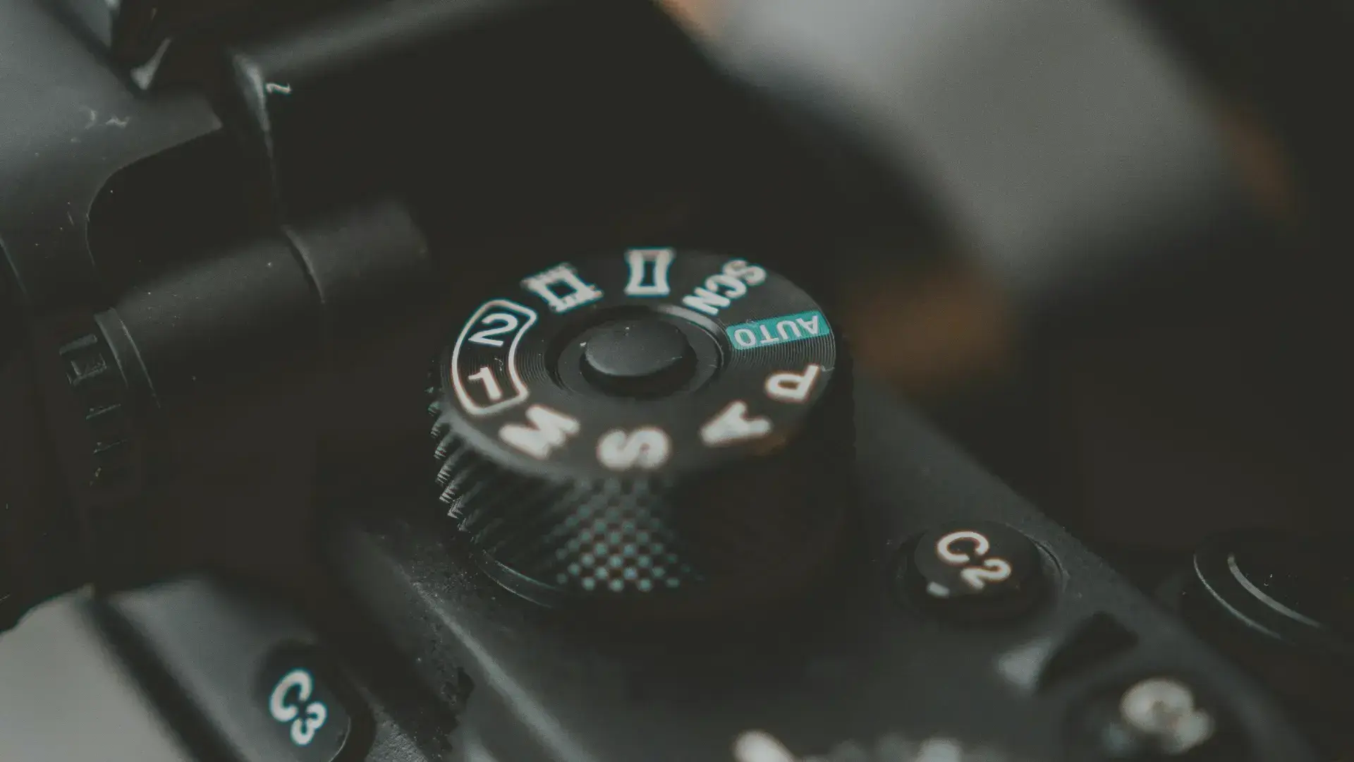 Close-up of a camera mode dial highlighting Manual (M), Aperture Priority (A), and Auto settings.